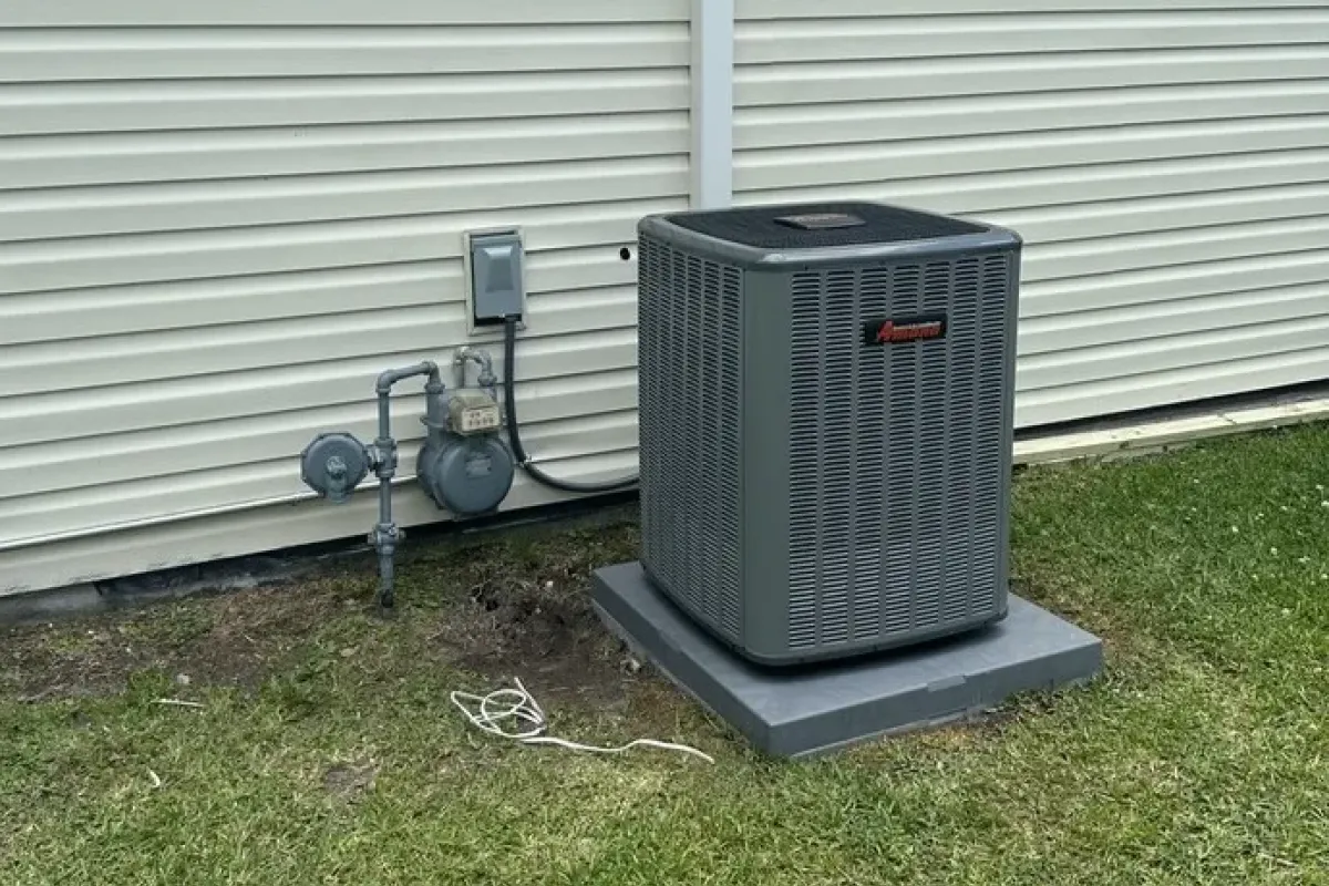 Amana outdoor AC condenser unit installed next to a residential siding wall.